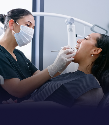 Dentist in a face mask insepcting a patient's teeth